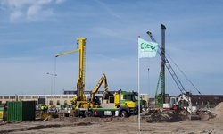 Het project Centrumeiland in Amsterdam-IJburg tijdens de bouwfase in 2018 met hijskranen en bouwvoertuigen en een wapperende Eteck-vlag