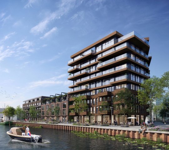 Een gebouw van 9 verdiepingen met lagere gebouwen eraan vast. Op de voorgrond is een kanaal.