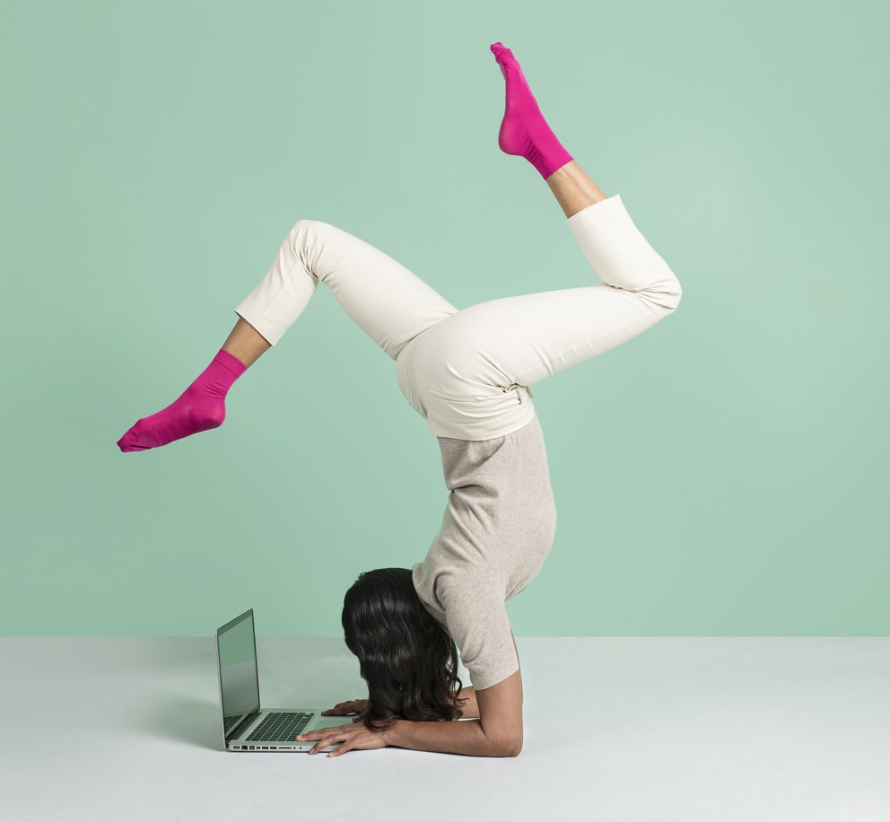 Een vrouw in ingewikkelde yogahouding die ondertussen werkt op haar laptop