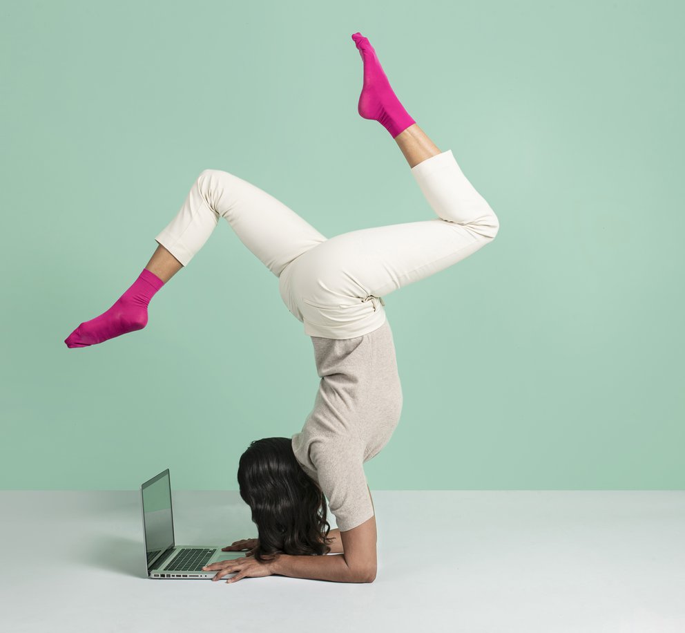 Een vrouw in ingewikkelde yogahouding die ondertussen werkt op haar laptop