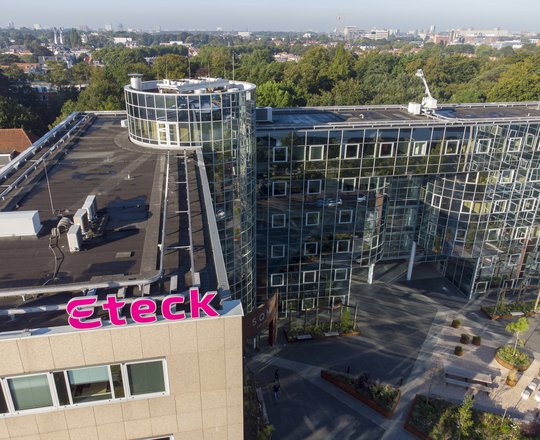 Bovenaanzicht van het kantoor gebouw van Eteck in Voorburg met het roze Eteck logo op het dak en op de achtergrond veel groen