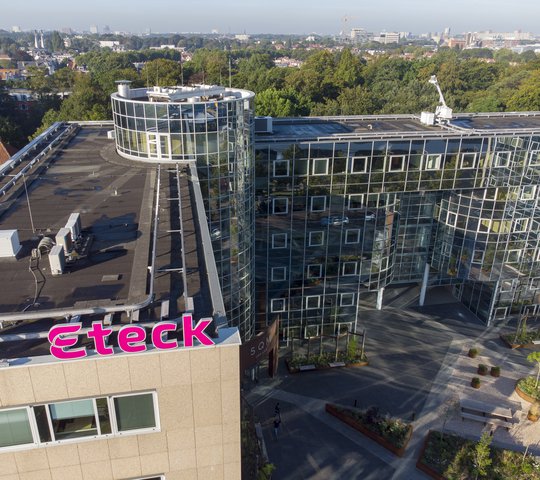Bovenaanzicht van het kantoor gebouw van Eteck in Voorburg met het roze Eteck logo op het dak en op de achtergrond veel groen