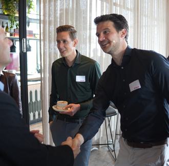 Twee personen schudden elkaar de hand bij een kennisevent