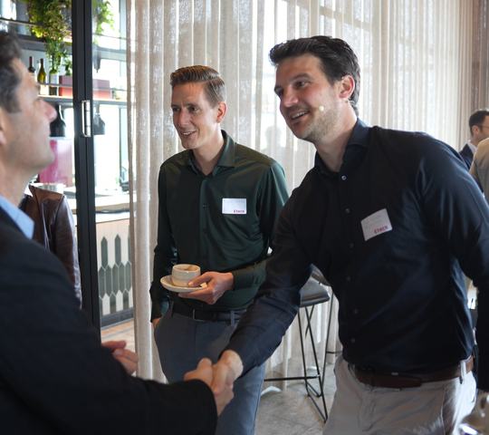 Twee personen schudden elkaar de hand bij een kennisevent