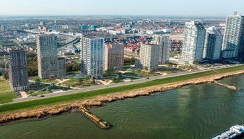 Bovenaanzicht van project Waterfront in Spijkenisse met negen hoge woontorens met parken met groen eromheen aan het water