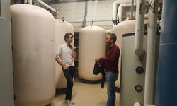 Twee mannen in een technische ruimte met grote witte ketels bij de servers van leafcloud waarbij Eteck gebruikmaakt van de warmte van apparatuur