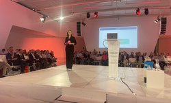 Jinny Moe Soe Let op een groot wit podium met rode sfeerverlichting tijdens het nationaal Warmtecongres